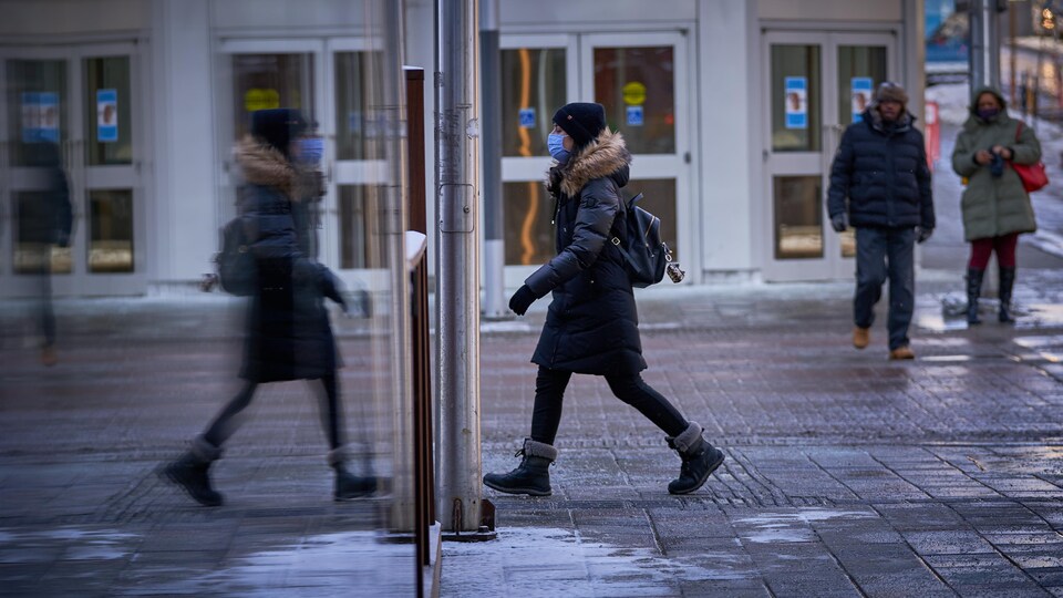 Une femme marche dans la rue avec un couvre-visage.