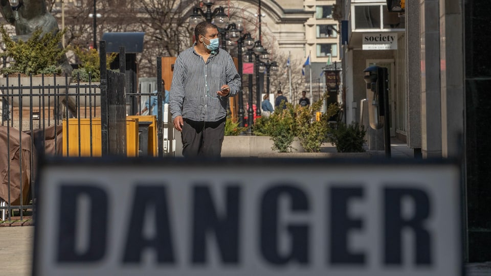 Un homme marche dans la rue avec un masque au visage.