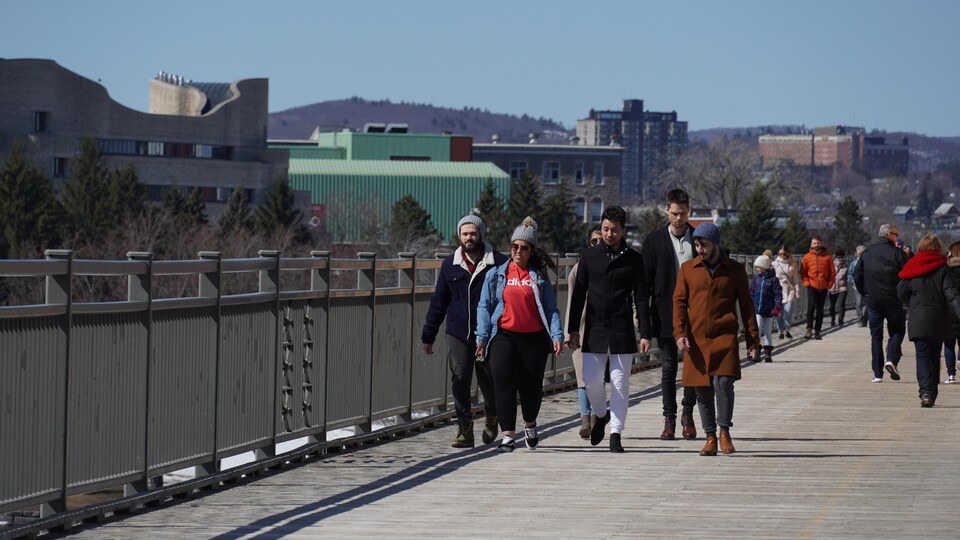 Des gens traversent un pont à la marche en petit groupe.