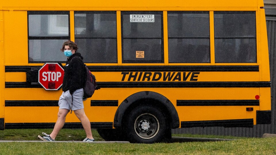 Un élève marche devant un autobus scolaire.
