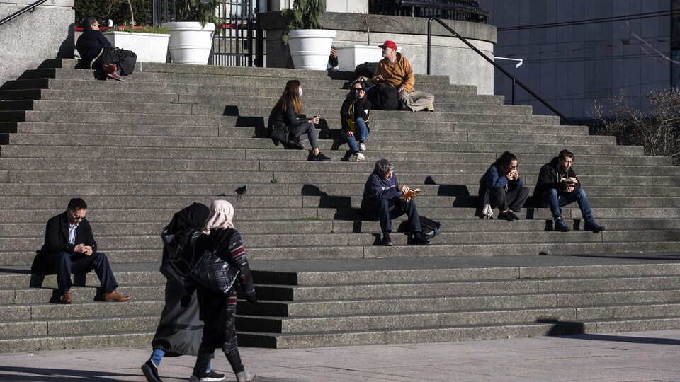 Des gens assis sur des marches alors que d'autres marchent.