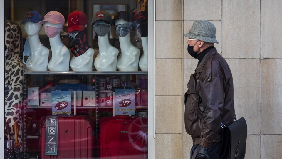 Une personne marche devant la vitrine d'une boutique qui vend des masques.