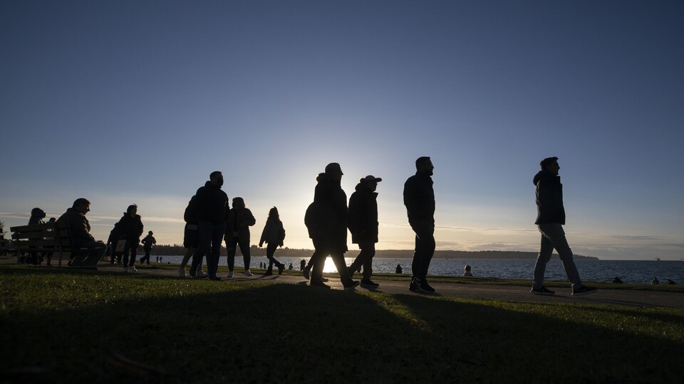Des gens marchent au bord de l'eau à Vancouver.