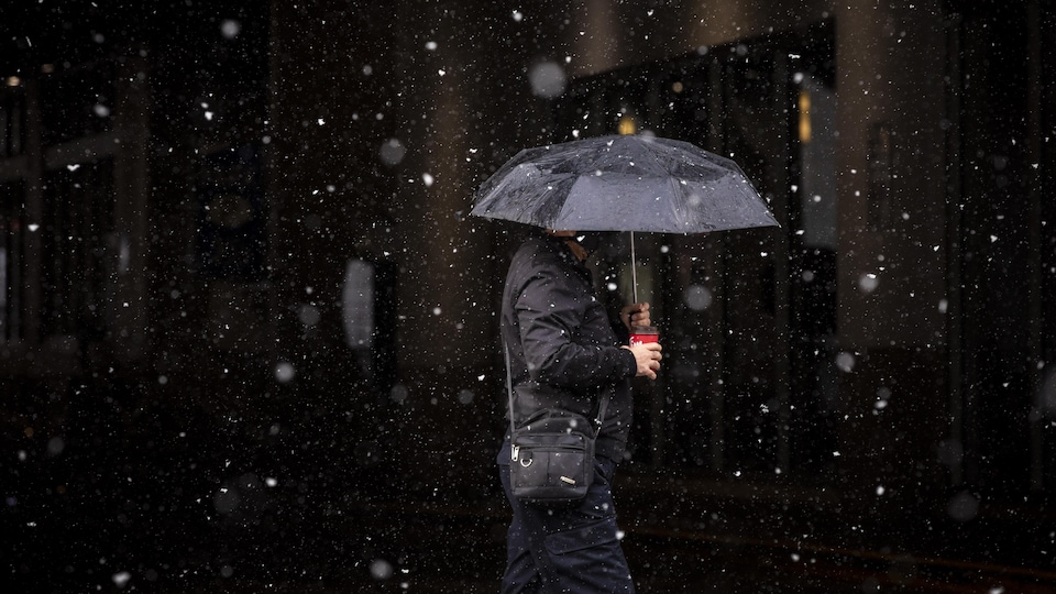 Un homme marche sous la pluie.