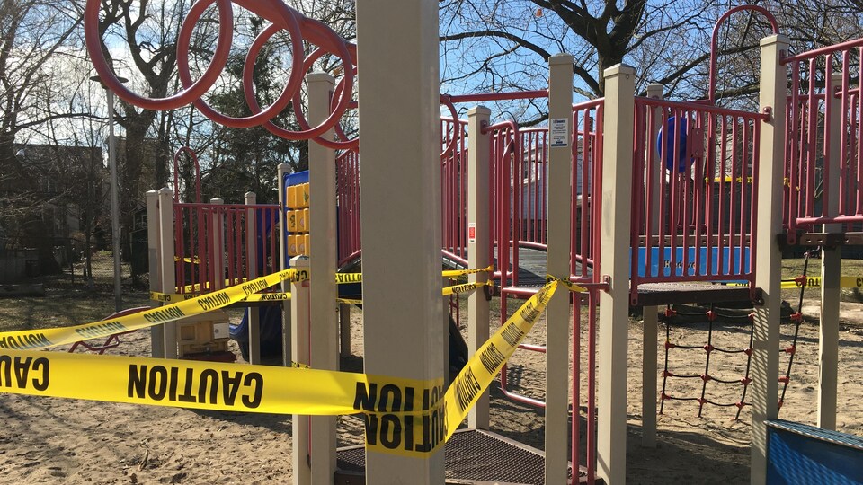 Une banderole jaune autour d'une structure de jeux dans un parc.