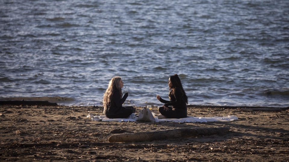 Deux jeunes femmes font un pique-nique sur la plage.