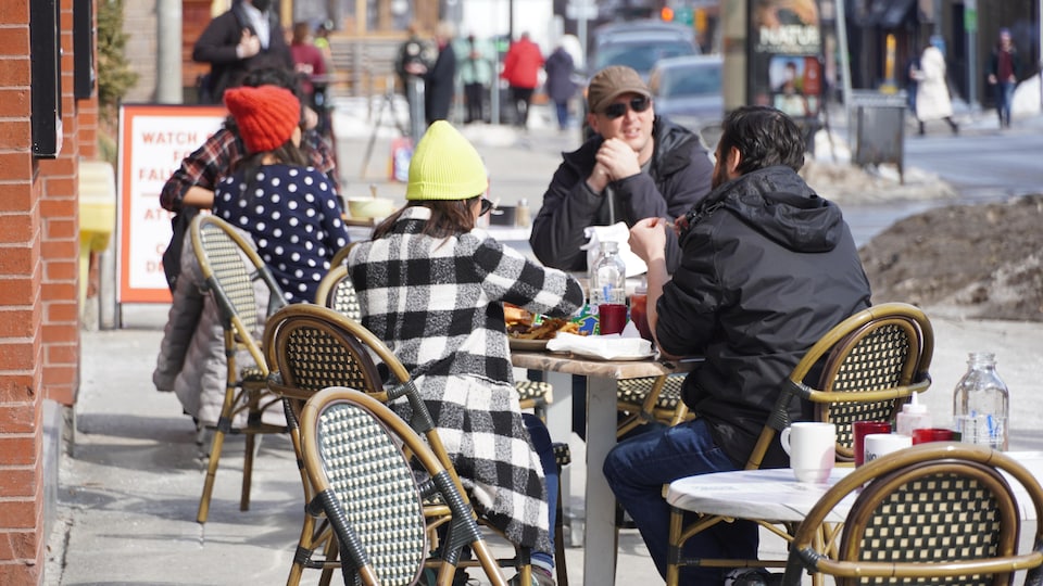Des gens partagent un repas sur une terrasse de restaurant.