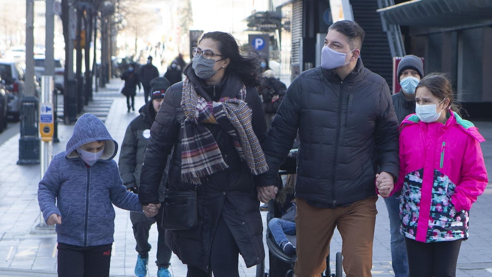 Une famille passe dans la rue près d'une manifestante antivaccin.