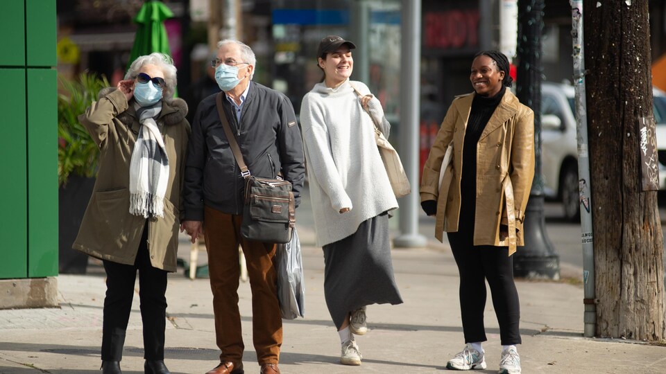 Des passants dans la rue à Toronto, certains portant un masque.