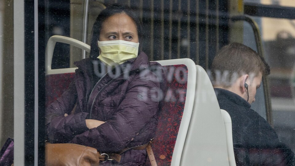 Une femme porte un masque assise dans un tramway.