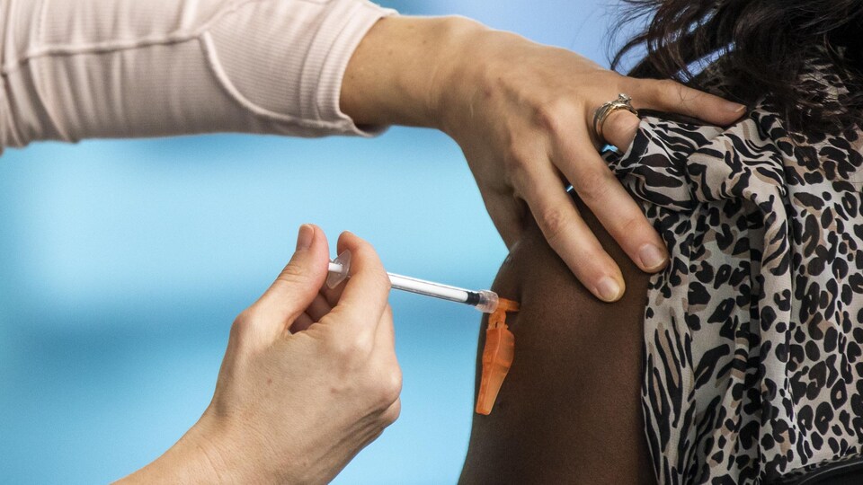 Une infirmière se fait vacciner contre la COVID-19.