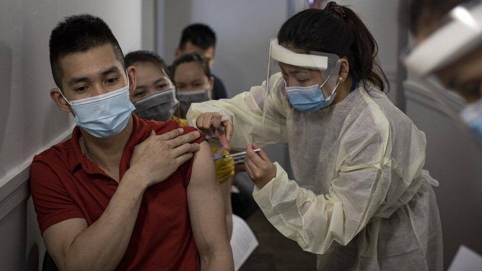 Un homme dans la vingtaine se fait vacciner à l'immeuble d'appartements où il habite, dans le quartier Jane et Finch, dans le nord-ouest de Toronto.