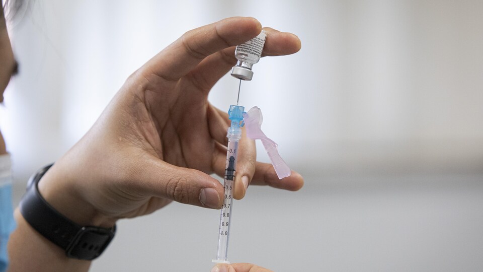 Un travailleur de la santé remplit une seringue de vaccin.