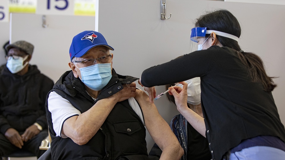 Un homme se fait injecter le vaccin dans l'épaule.