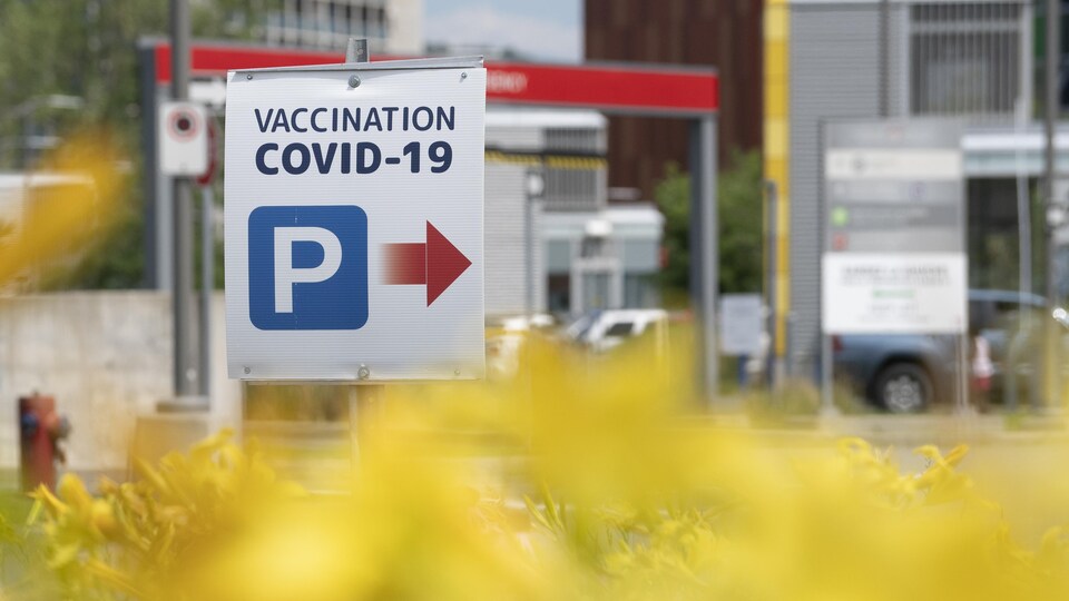 Une pancarte indiquant la direction pour accéder à une clinique de vaccination.