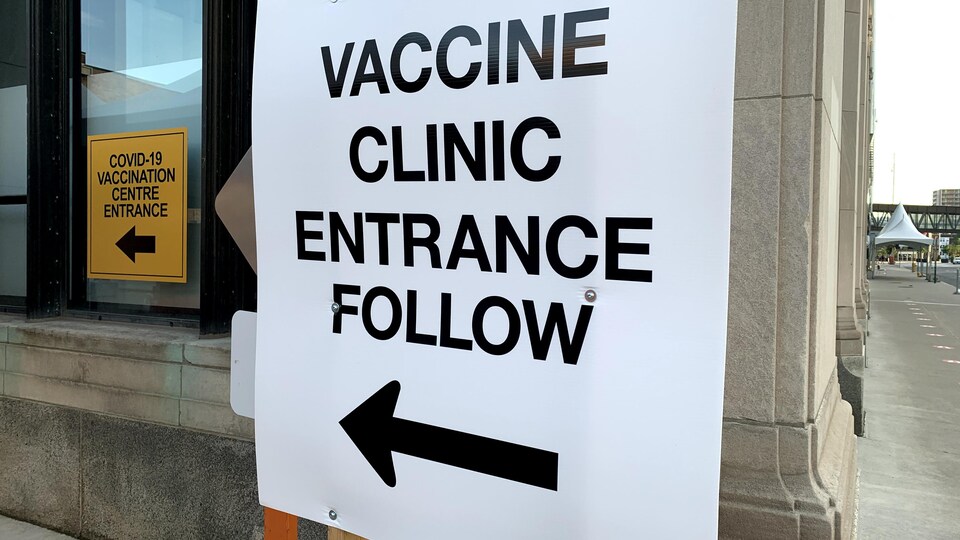 Un panneau indique où se situe l'entrée de la clinique de vaccination.