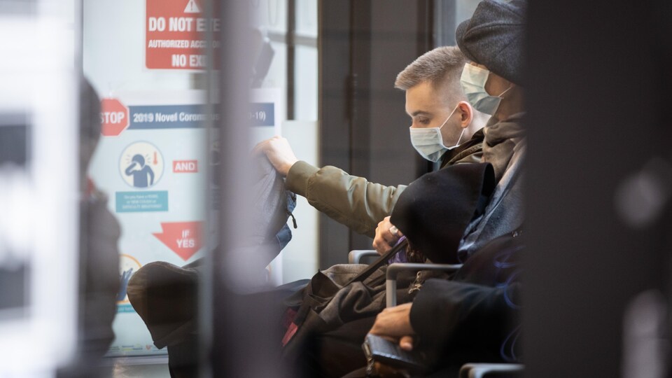 Deux hommes masqués assis dans un corridor.