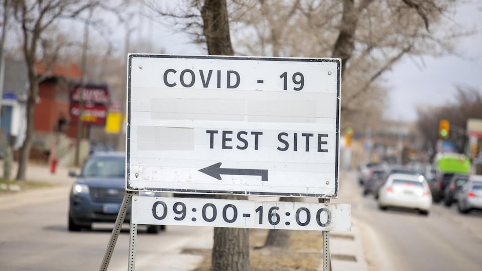 Une affiche indique par une flèche l'entrée d'un centre communautaire pour les tests de dépistage de la COVID-19.