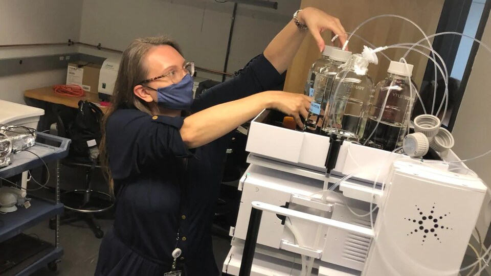 Une femme masquée ajuste des échantillons liquides.