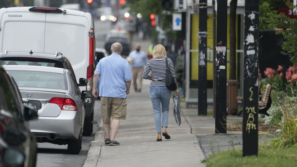 Deux personnes marchant sur un trottoir.