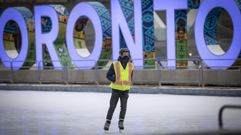 Un homme immobile sur une patinoire devant les lettres lumineuses de Toronto.