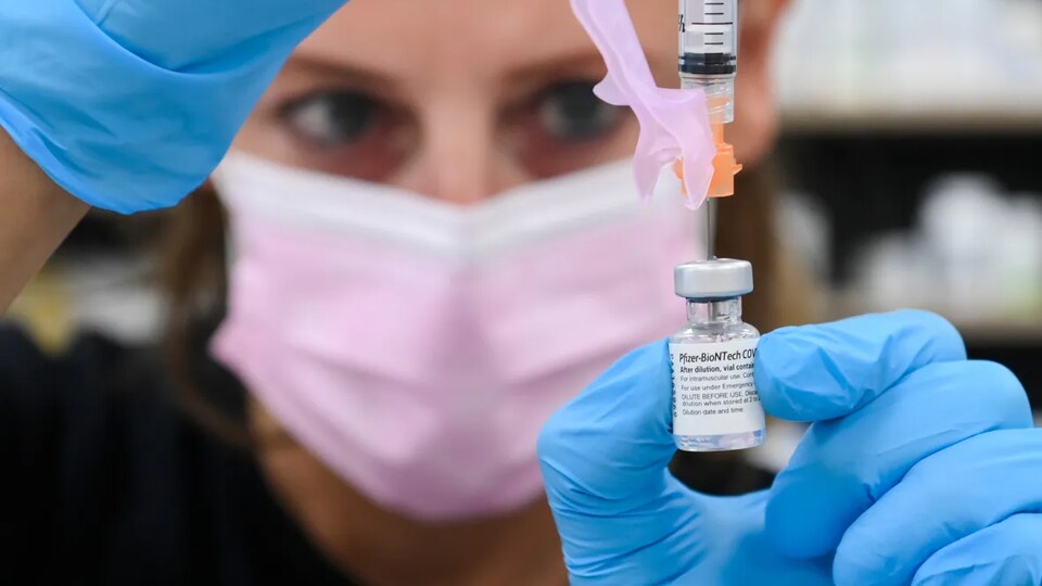 Une pharmacienne prépare une dose de vaccin Moderna.