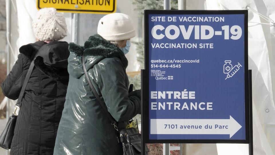 Des personnes entrent dans un centre de vaccination contre la COVID-19 à Montréal. 