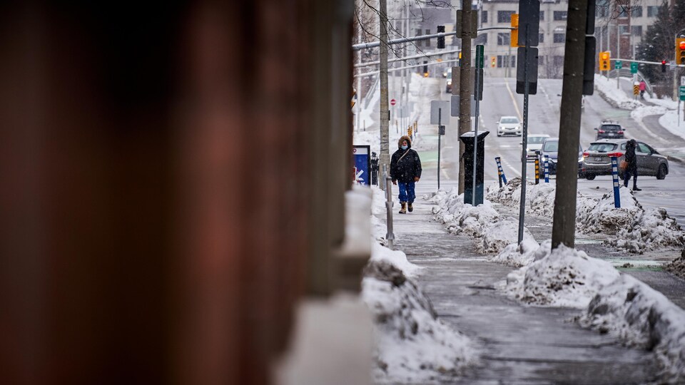 Un homme marche dans la rue en hiver.