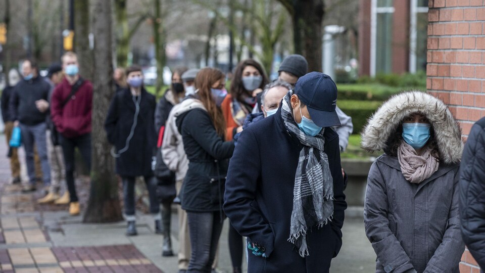 Des clients font la queue pour entrer dans un magasin BC Liquor au centre-ville de Vancouver, en Colombie-Britannique, le jeudi 31 décembre 2020.