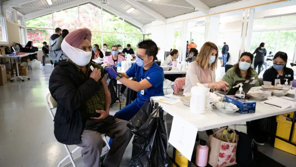 Un homme en train de se faire vacciner.