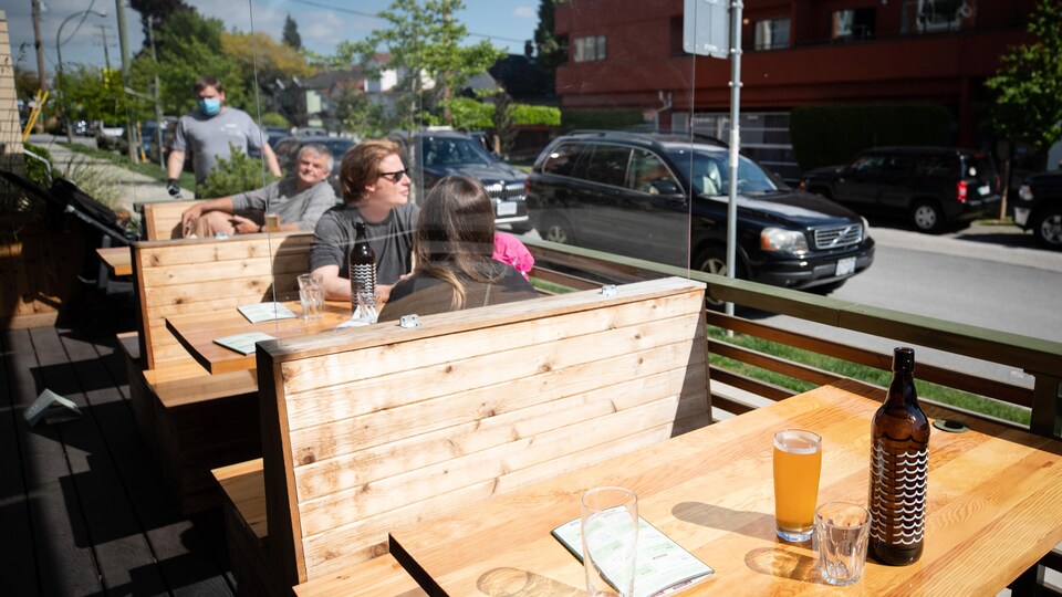 Des barrières de plexiglas séparent les tables sur la patio du restaurant Bells and Whistles.