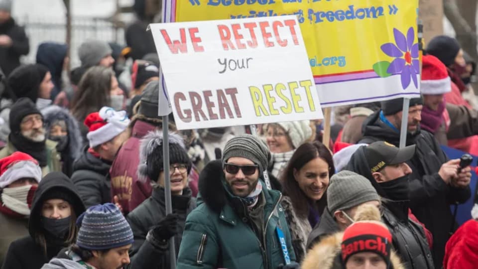 Des manifestants portent une pancarte sur laquelle est écrit « we reject your great reset ».