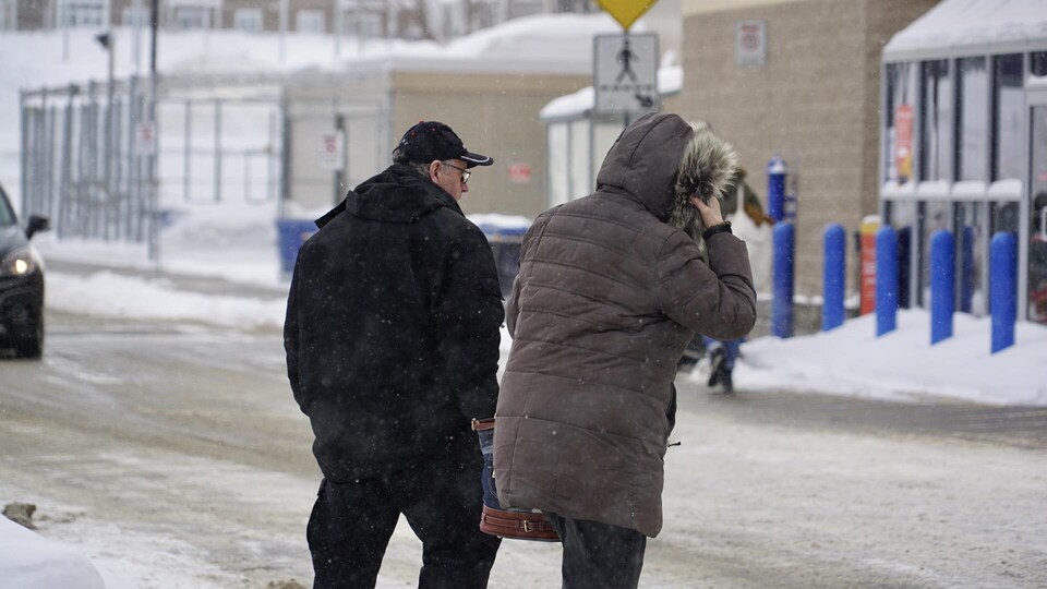 Des passants traversent une rue à Rimouski.
