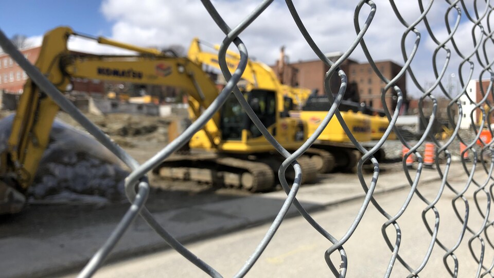 Derrière une clôture métallique, des pelles mécaniques sur le chantier de construction Well Sud au centre-ville de Sherbrooke