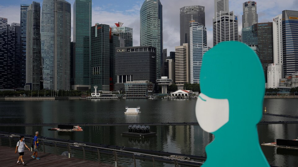 Une statue portant un masque devant une vue de la marina de Singapour.