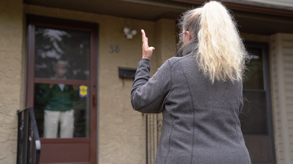 Un ainé discute avec une bénévole derrière sa fenêtre.