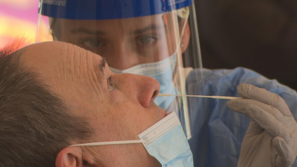 Une infirmière effectue un test de dépistage de la COVID-19 sur un patient. 