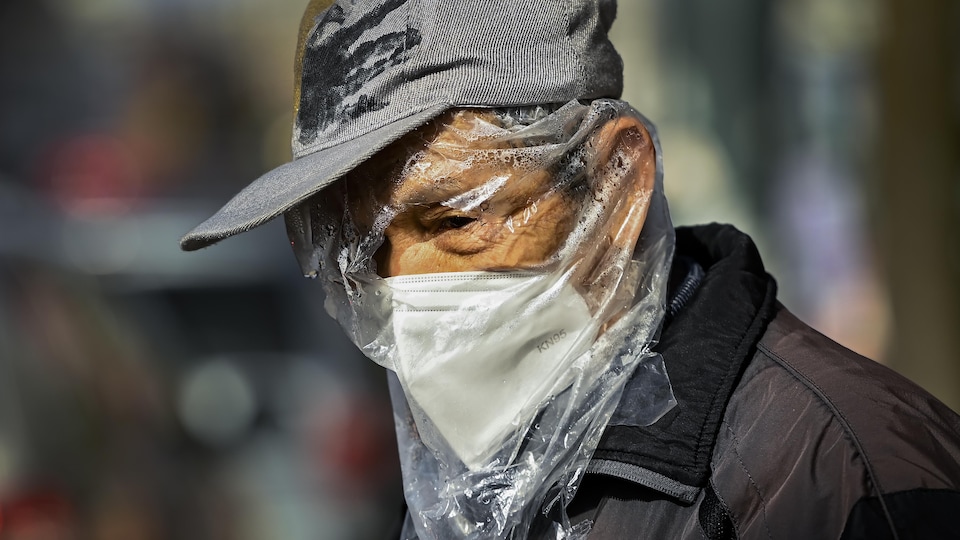 L'homme a un masque et un sac de plastique transparent sur la tête avec des trous pour les yeux.