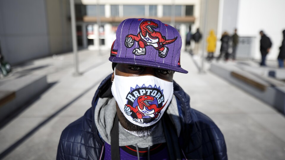 Un consommateur portant une casquette et un masque des Raptors devant le centre commercial Vaughan Mills.