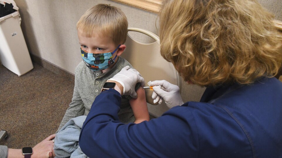 Un enfant se fait injecter le vaccin contre la COVID-19 dans l'épaule.