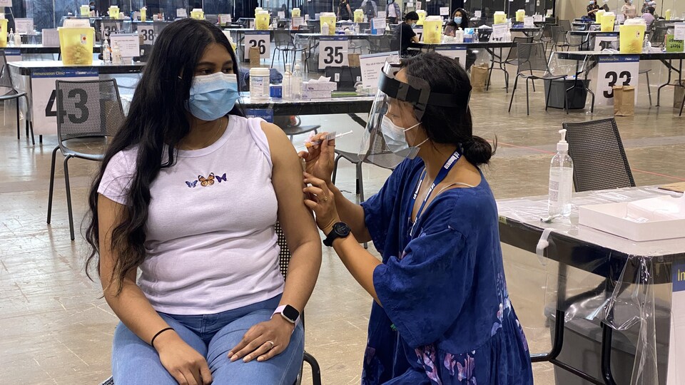 Une Torontoise se fait injecter le vaccin dans l'épaule dans un centre d'immunisation de masse.