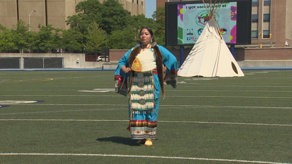 Une Autochtone en costume traditionnel danse au stade Varsity.