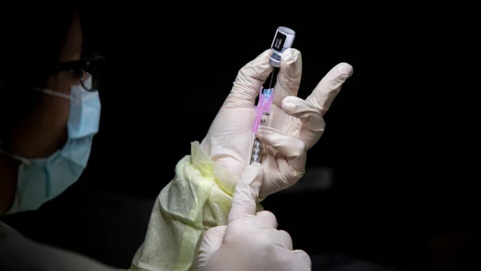 Une personne prépare une dose du vaccin contre la COVID-19.