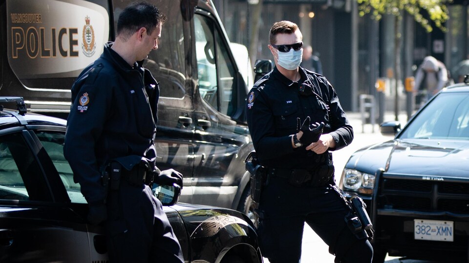 Deux policiers de Vancouver au centre-ville. L'un d'eux porte un masque. 