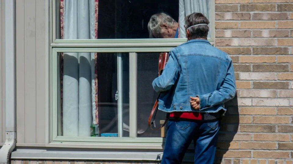 Deux personnes sont séparées par une fenêtre