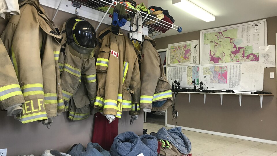 Dans une des salles de la caserne, les uniformes, les casques et le reste de l'équipement des pompiers volontaires sont accrochés.