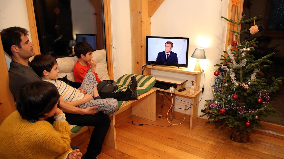 Une famille écoute le discours du président français, Emmanuel Macron.