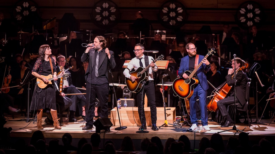 The four members of the Cowboys Fringants play music on the Maison symphonique stage. You can see the OSM musicians in the back.