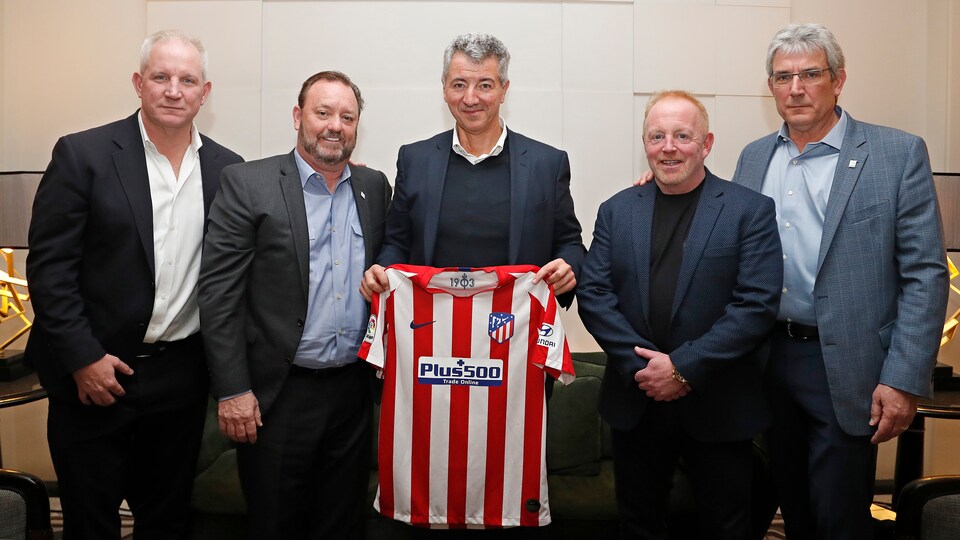Cinq homme qui posent pour une photo avec un chandail de l'Atletico Madrid.