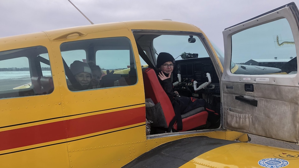 Un enfant envoie la main depuis le siège passager avant de l'avion.